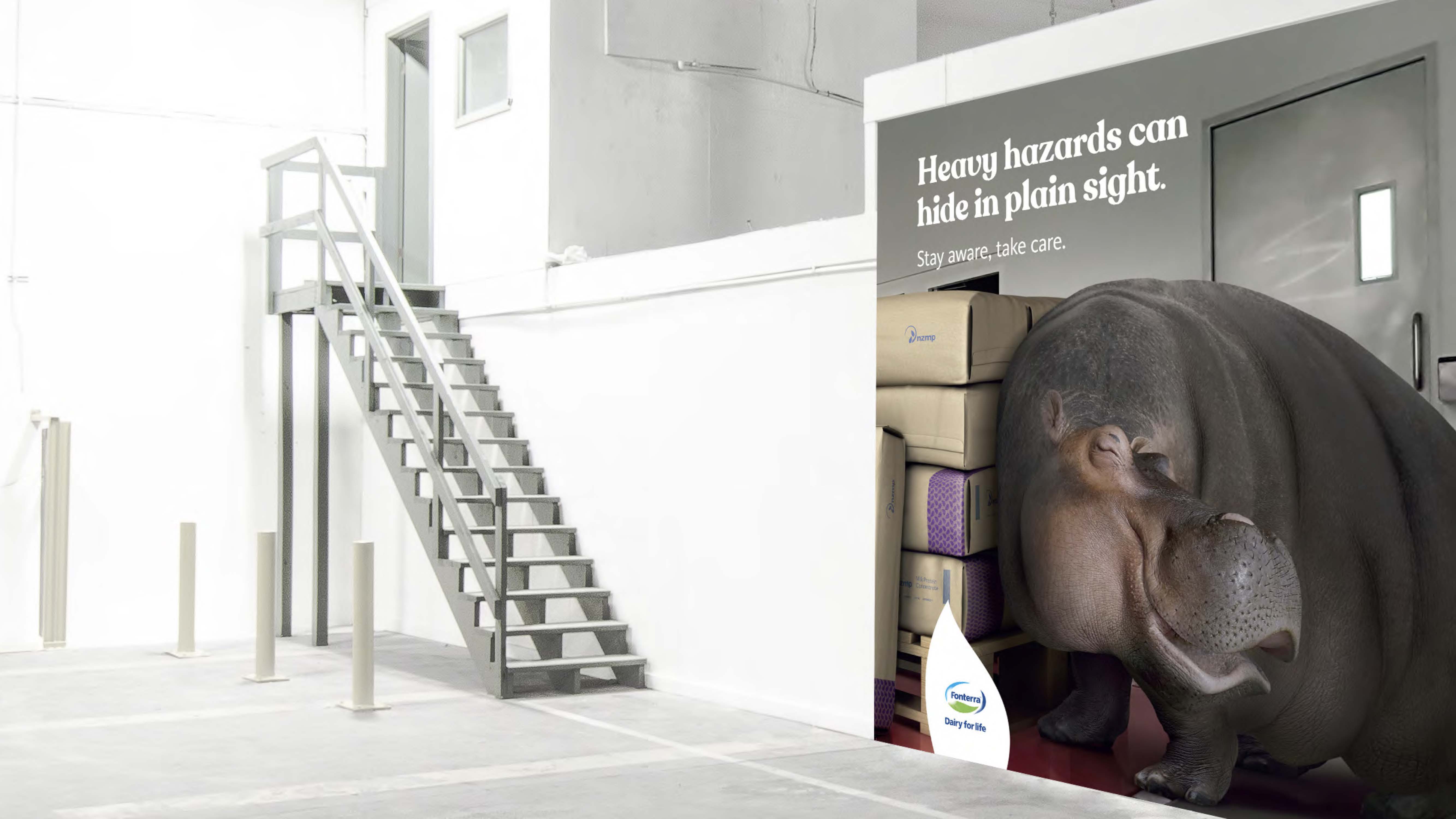Danger in Disguise OOH detail: a hippo standing beside a factory door under the line 'Heavy hazards can hide in plain sight. Stay aware, take care.'